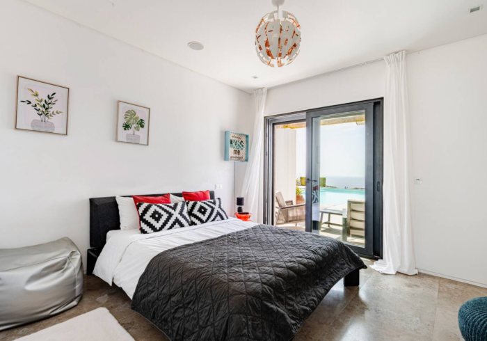 The Atlantic Room: Schlafzimmer mit geöffneten Glastüren zur Terrasse und zum Meer