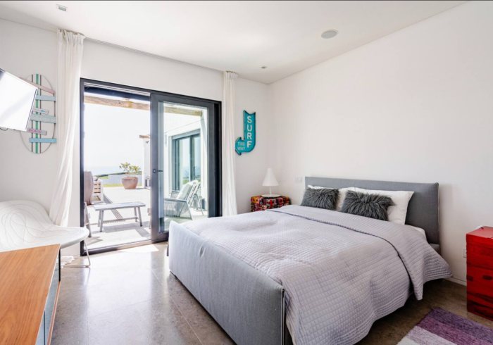 The Onda Room: Schlafzimmer mit Surf-Schild und Glastüren zur Terrasse