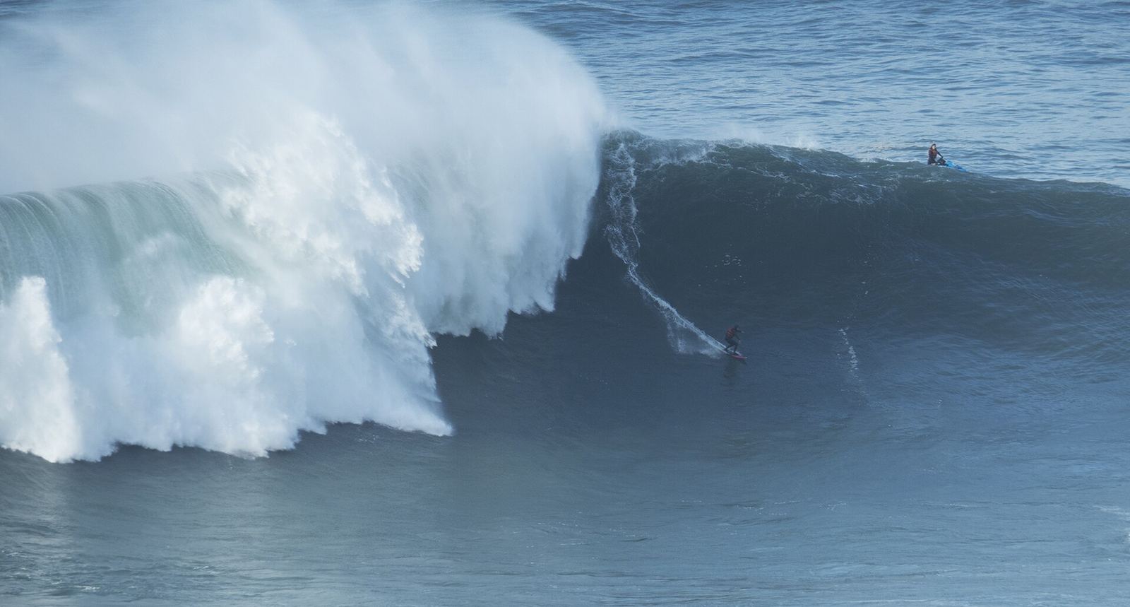 A surfer dropping down a giant wave at Praia do Norte, Nazaré